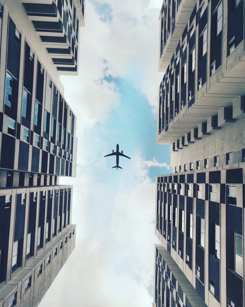 Photo of airplane above flying in between two buildings, photo from Pexels by Salih Sayed